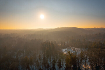 Fototapeta premium An aerial view of a misty sunrise over a forested valley with ruins in winter, in Hamilton, Ontario, Canada.