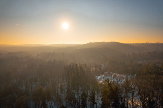 An aerial view of a misty sunrise over a forested valley with ruins in winter, in Hamilton, Ontario, Canada.