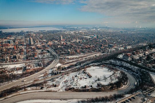 An aerial view of a dense urban cityscape with highways in the bright sunny morning light during winter in Hamilton, Ontario, Canada.