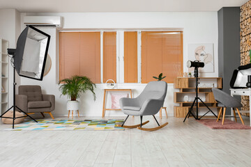 Interior of modern photo studio with lighting equipment and furniture