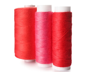 Pink and red sewing thread spools on white background