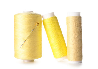 Yellow sewing thread spools with pin on white background