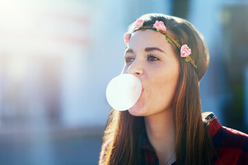 Freedom is a state of mind. Shot of an attractive young woman blowing chewing gum outside.