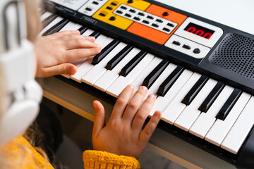 Plakat a little girl playing the synthesizer, the concept of teaching children music, hands close-up