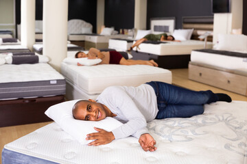 Obraz na płótnie Canvas Young man fell asleep on new mattress in a furniture store