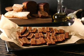 Baking sheet with tasty rye croutons on table
