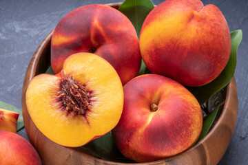 Sweet Yellow Peach with slice in wooden basket, Fresh Yellow Peach fruit in wooden bowl on wooden background.