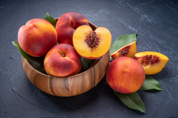 Yellow Peach with slice in wooden basket, Fresh Yellow Peach fruit in wooden bowl on wooden background.