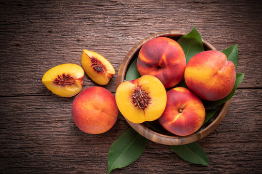 Yellow Peach with slice in wooden basket, Fresh Yellow Peach fruit in wooden bowl on wooden background.