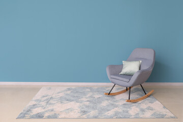 Modern armchair and carpet near blue wall