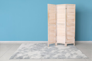 Wooden folding screen and carpet near blue wall