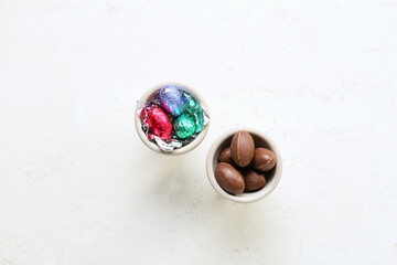 Holders with chocolate Easter eggs on light background