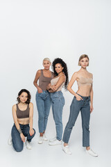 Obraz premium Young women posing near interracial friends on grey background.