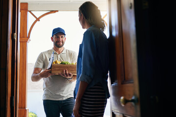 Fototapeta premium Well deliver whatever you need from the grocery store. Shot of a courier delivering groceries to a customer at her home.