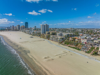 Aerial view looking at a sandy beach of an urban coastal resort community.   - obrazy, fototapety, plakaty