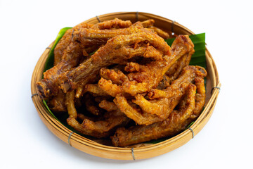 Fried chicken feet in bamboo basket on white background.