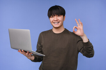 Asian korean young coder programmer student man freelancer hacker working remotely on laptop, doing...