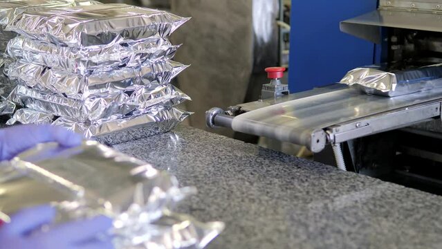 The plastic packaging machine on the production line packs food products. Humanitarian aid. Packaging of products at the enterprise.Robotic Production Line