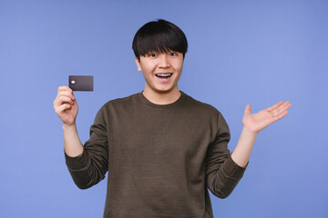 Impressed smiling young asian man korean boy holding showing credit card for loan, cashback, online...