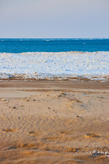 Layers on beach during winter of water, ice, and sand