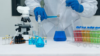 Fototapeta premium Scientist's hand tool holding a bottle with laboratory glassware in the background of a chemistry lab. Research and development concepts in science laboratories Medicine and Biotechnology