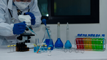Scientist's hand tool holding a bottle with laboratory glassware in the background of a chemistry...