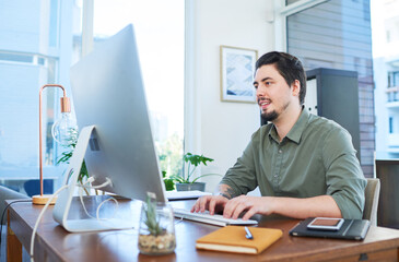 Working hard to make success his. Shot of a young businessman working on a computer in an office.