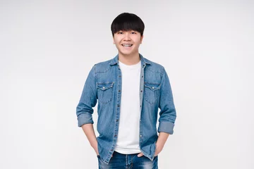 Fotobehang Smiling confident asian korean boy man student freelancer in denim shirt looking at the camera isolated on white background. © InsideCreativeHouse