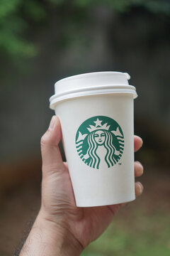 Male hand holding starbucks cup on blur background.