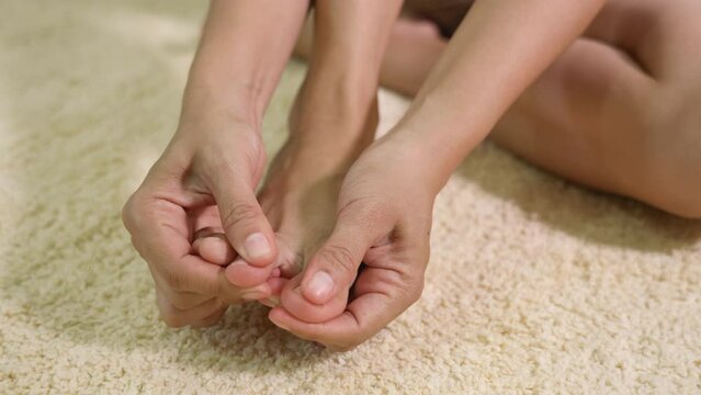 Foot pain, Asian woman holds her toe injury feeling pain her foot at home, female suffering from feet ache use hand massage relax muscle from toe in house interior, Healthcare problems medical concept