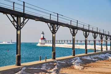 Lighthouse through opening of walkway on beach by water