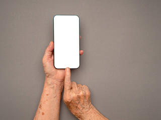 Top view of old woman hand holding a mobile phone with copy space for text over a gray background