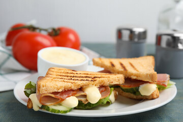 Delicious sandwiches with vegetables, ham and mayonnaise on plate, closeup