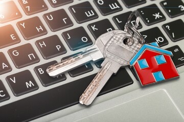House key and home symbol shaped keychain on laptop keyboard online internet property search concepts
