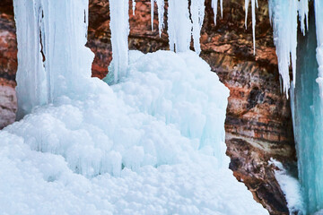 Ice formations from melting snow next to cliffs detail