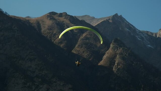 a lot of paragliders fly in the mountains, a bunch of paragliders hover over the rocks