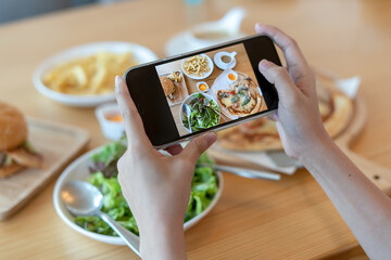 italian food. The restaurant owner takes a picture of the food on the table with a smartphone to post on a website. Online food delivery and ordering service