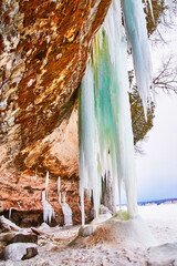 Cave opening in cliffs during winter with large icicles dangling