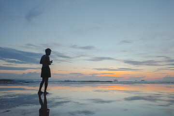 After sunset at the beach, Young man walking and looking the sky stand alone feel lonely.