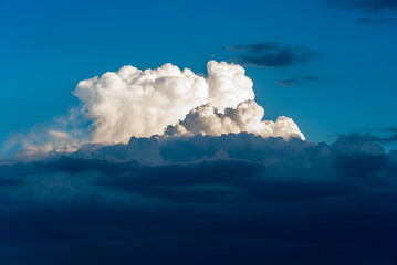 Naklejka premium A large cloud formation is brightly lit by the sun while dark storm clouds are below
