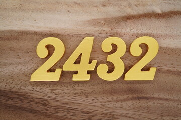 Golden Arabic numerals on a real brown and white wooden floor number 2432