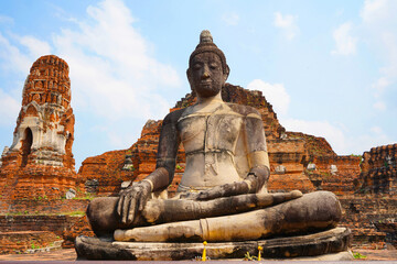 Buddha image in front of the main pagoda of Wat Mahathat Ayutthaya Historical Park, Thailand.                   - obrazy, fototapety, plakaty