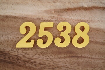 Golden Arabic numerals on a real brown and white wooden floor number 2538