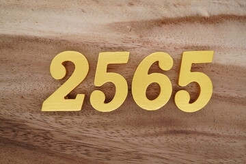 Golden Arabic numerals on a real brown and white wooden floor number 2565