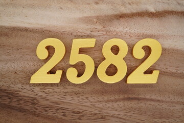 Golden Arabic numerals on a real brown and white wooden floor number 2582