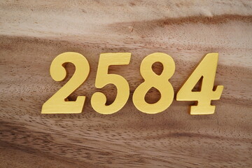 Golden Arabic numerals on a real brown and white wooden floor number 2584