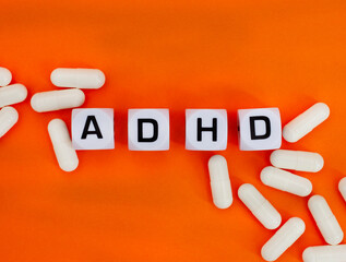 ADHD in letter dice on orange background, the color of ADHD awareness
