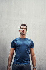 The impossible is merely in your mind. Shot of a sporty young man standing against a grey wall while exercising outdoors.