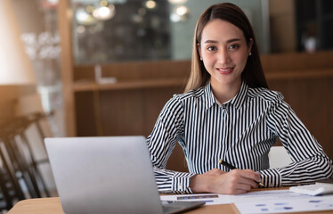 Charming asian businesswoman sitting working on laptop in office.