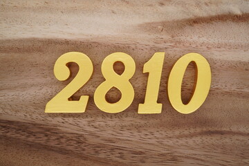 Golden Arabic numerals on a real brown and white wooden floor number 2810